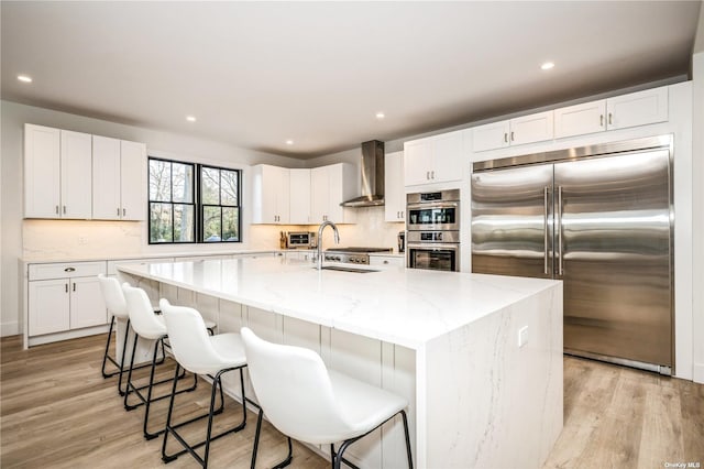 1350 Hortons Ln, Southold, NY 11971 - kitchen with appliances with stainless steel finishes, wall chimney range hood, light wood-style flooring, light stone countertops, and recessed lighting