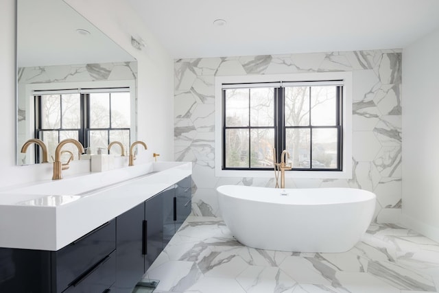 1350 Hortons Ln, Southold, NY 11971 - bathroom featuring plenty of natural light, marble tiled floors, double vanity, a soaking tub, and tile walls