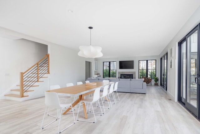 1350 Hortons Ln, Southold, NY 11971 - dining area with light wood-type flooring, a glass covered fireplace, stairway, and baseboards