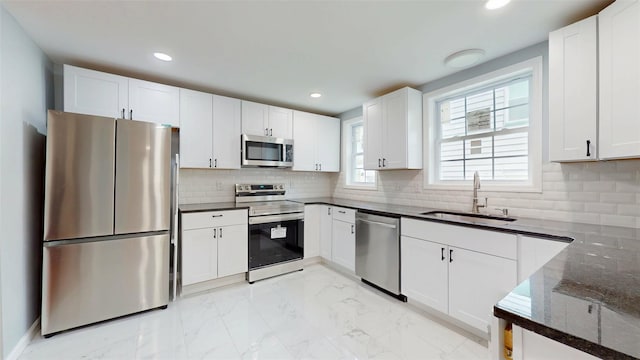 74 Gladstone Ave, Walden, NY 12586 - kitchen with appliances with stainless steel finishes, a sink, light marble finish floors, dark stone counters, and white cabinets