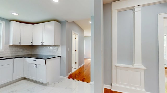 74 Gladstone Ave, Walden, NY 12586 - kitchen with light marble finish floors, white cabinets, decorative backsplash, dark countertops, and baseboards