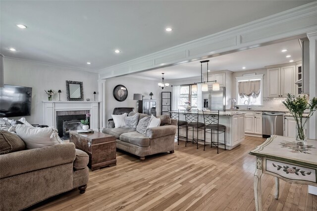 living room featuring light wood finished floors, a fireplace, crown molding, and recessed lighting