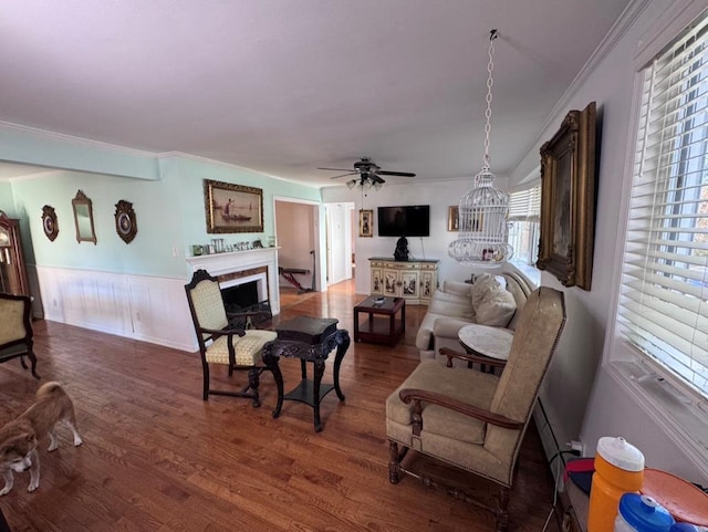 980 Siems Ct, North Bellmore, NY 11710 - living room featuring wood finished floors, a fireplace, a ceiling fan, ornamental molding, and wainscoting