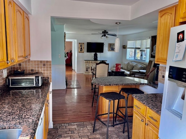 980 Siems Ct, North Bellmore, NY 11710 - kitchen with white fridge with ice dispenser, a kitchen bar, open floor plan, a ceiling fan, and dark stone counters