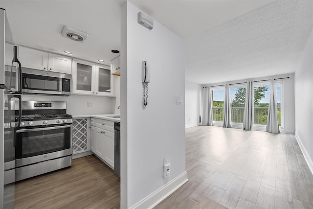 10 Stewart Pl Unit 4De, White Plains, NY 10603 - kitchen featuring stainless steel appliances, wood finished floors, white cabinetry, and baseboards