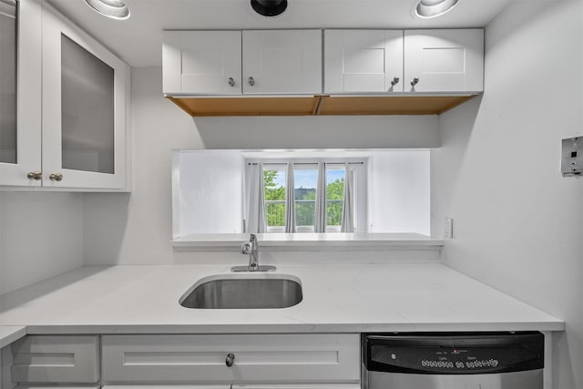 10 Stewart Pl Unit 4De, White Plains, NY 10603 - kitchen featuring stainless steel dishwasher, a sink, white cabinetry, glass insert cabinets, and light stone counters