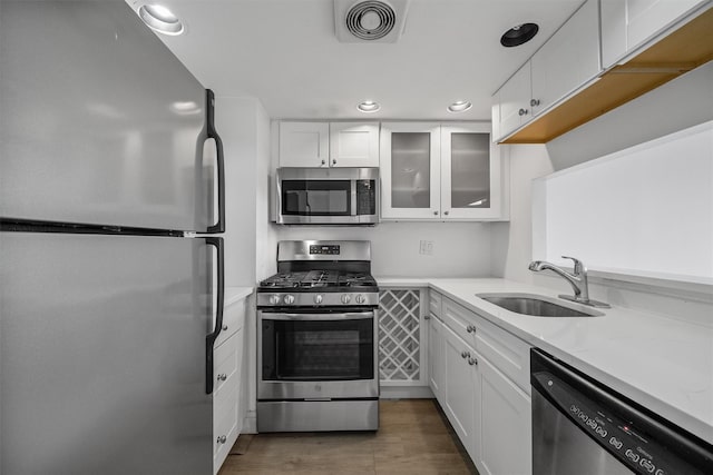 10 Stewart Pl Unit 4De, White Plains, NY 10603 - kitchen with appliances with stainless steel finishes, a sink, white cabinetry, glass insert cabinets, and recessed lighting