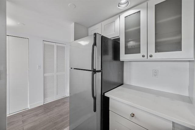 10 Stewart Pl Unit 4De, White Plains, NY 10603 - kitchen featuring freestanding refrigerator, white cabinets, light countertops, glass insert cabinets, and light wood finished floors