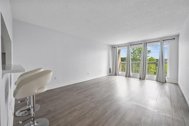 10 Stewart Pl Unit 4De, White Plains, NY 10603 - unfurnished living room featuring a textured ceiling, wood finished floors, and baseboards