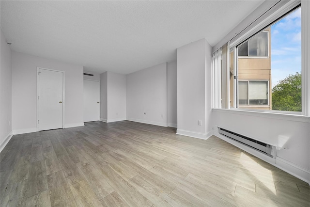 10 Stewart Pl Unit 4De, White Plains, NY 10603 - unfurnished living room with a baseboard heating unit, wood finished floors, and baseboards