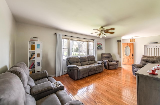 living room featuring light wood-style floors, a ceiling fan, baseboards, and baseboard heating