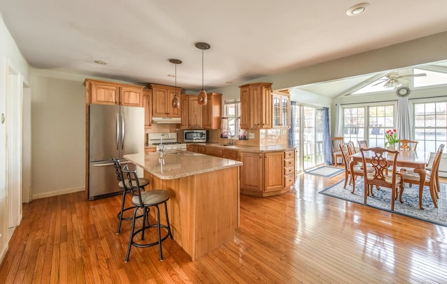 kitchen featuring appliances with stainless steel finishes, plenty of natural light, a sink, a kitchen island with sink, and recessed lighting