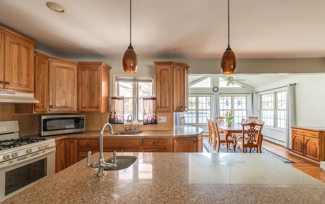 kitchen featuring white range with gas cooktop, stainless steel microwave, under cabinet range hood, and a sink
