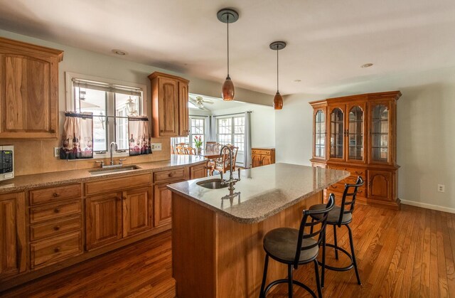 kitchen with a sink, brown cabinets, a breakfast bar area, and recessed lighting
