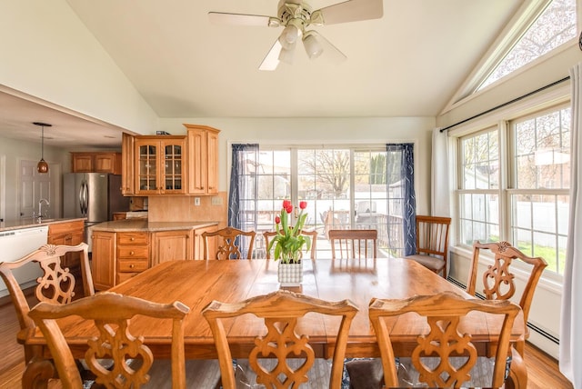 dining area featuring a baseboard heating unit, ceiling fan, light wood-style floors, and high vaulted ceiling