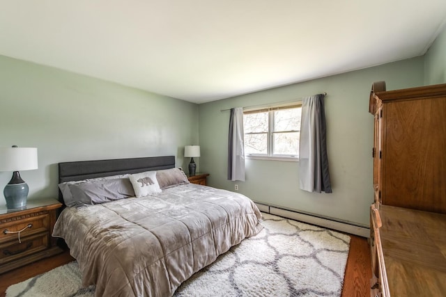 bedroom with a baseboard heating unit and wood finished floors