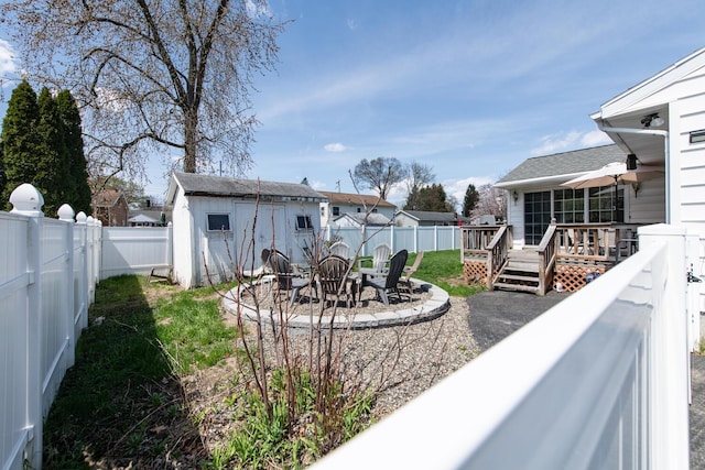 fenced backyard with a deck, an outbuilding, a storage unit, and outdoor dining area