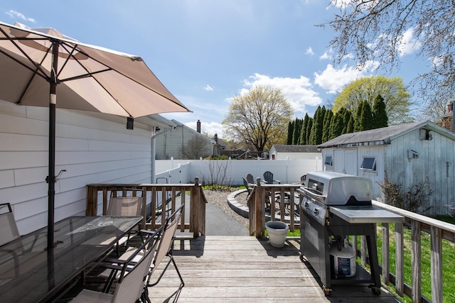 wooden terrace with outdoor dining area, a fenced backyard, area for grilling, and an outdoor structure