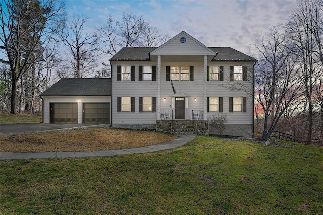view of front of home with asphalt driveway, an attached garage, and a lawn