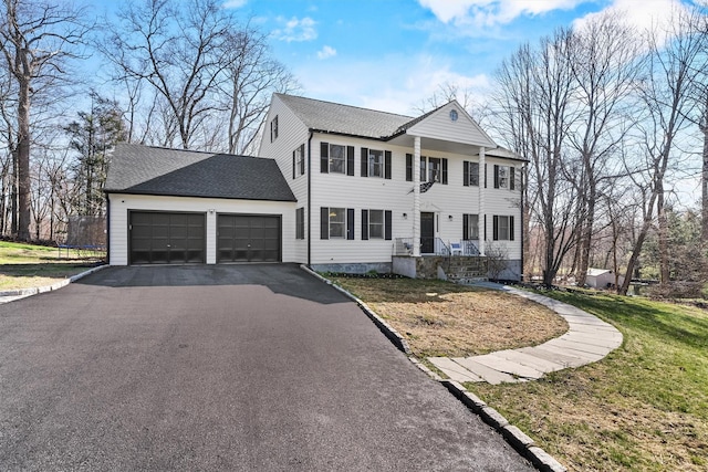 view of front of home featuring an attached garage, driveway, a front yard, a trampoline, and roof with shingles