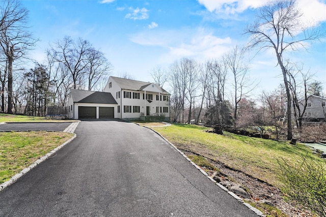 colonial inspired home featuring an attached garage, a front yard, and driveway