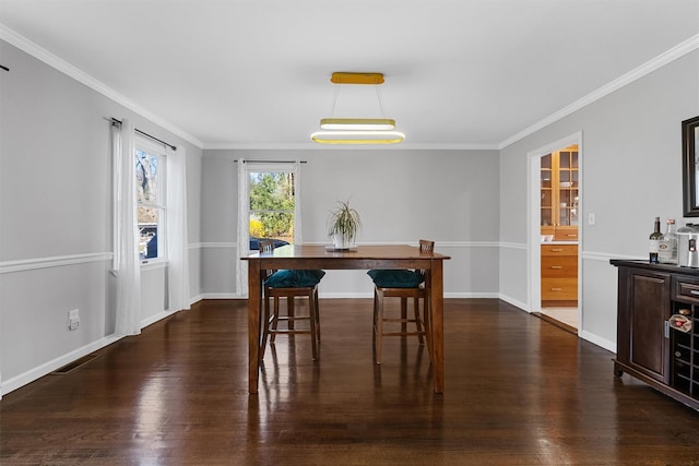 dining space featuring dark wood-style floors, crown molding, and baseboards