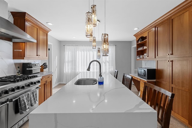 kitchen with stainless steel stove, a sink, wall chimney exhaust hood, black microwave, and a kitchen island with sink