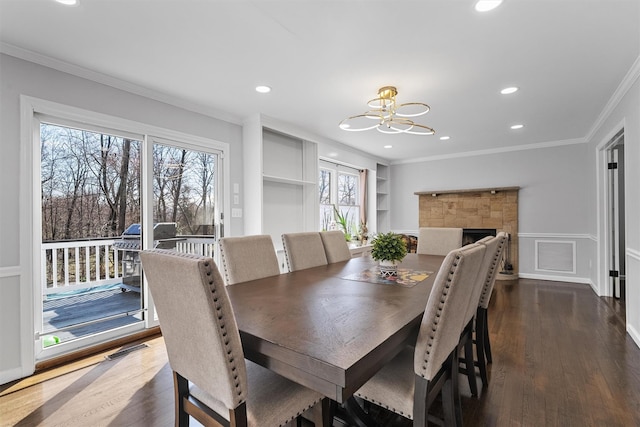 dining space featuring a chandelier, crown molding, dark wood-style flooring, recessed lighting, and built in shelves