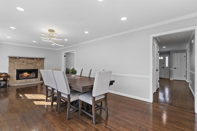 dining room with wood finished floors, a chandelier, ornamental molding, recessed lighting, and a stone fireplace