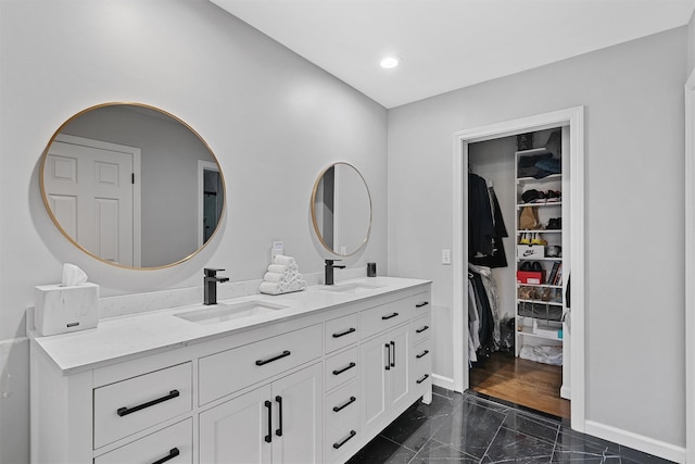full bathroom featuring double vanity, baseboards, a spacious closet, recessed lighting, and marble finish flooring