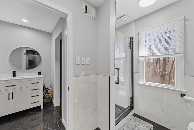 bathroom featuring a stall shower, wainscoting, marble finish floors, and vanity