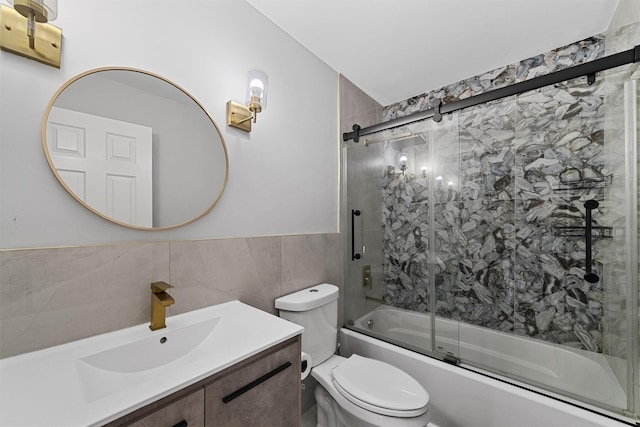 full bath featuring bath / shower combo with glass door, vanity, tile walls, and toilet