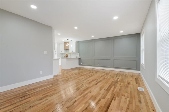 spare room featuring light wood-type flooring, a decorative wall, baseboards, and recessed lighting