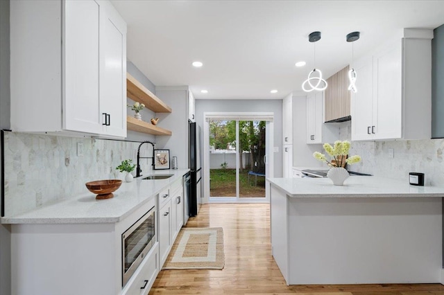 kitchen featuring a sink, appliances with stainless steel finishes, open shelves, a peninsula, and white cabinets