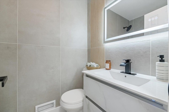 bathroom with tile walls, toilet, and vanity