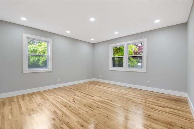 empty room featuring light wood finished floors, baseboards, and recessed lighting