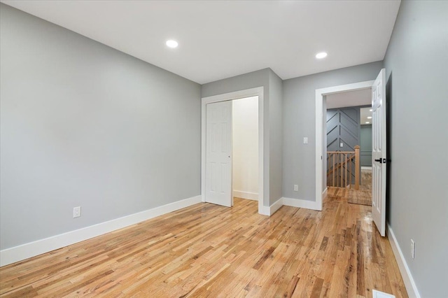 unfurnished bedroom with light wood-style flooring, baseboards, recessed lighting, and a closet