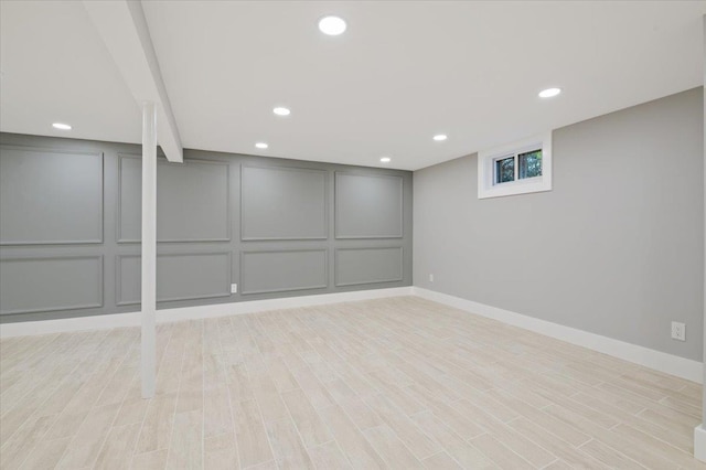 basement featuring a decorative wall, light wood finished floors, baseboards, and recessed lighting