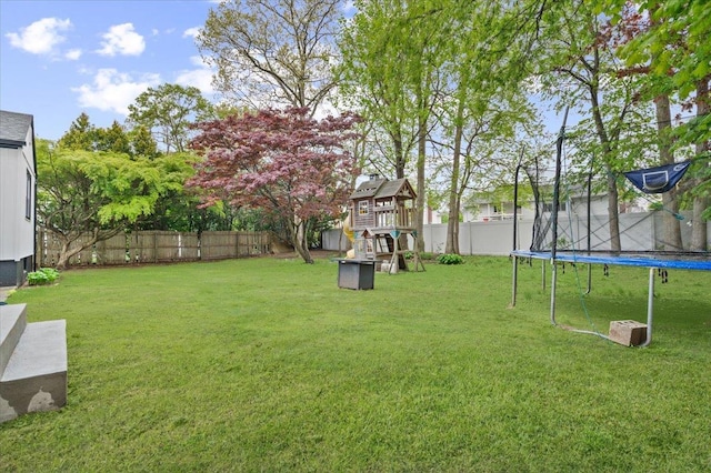 view of yard with a trampoline and a playground