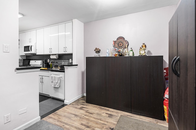 kitchen featuring white appliances, light wood-style floors, white cabinets, dark countertops, and backsplash