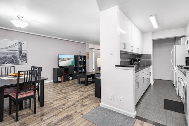 kitchen with dark countertops, white cabinets, tasteful backsplash, dark wood-style flooring, and baseboards