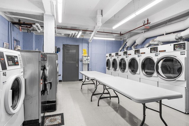 shared laundry room featuring separate washer and dryer, light floors, and concrete block wall