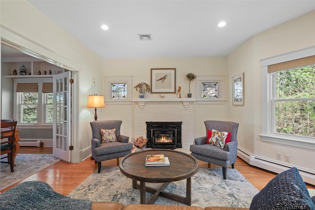 living room with a baseboard radiator, wood finished floors, a brick fireplace, and recessed lighting