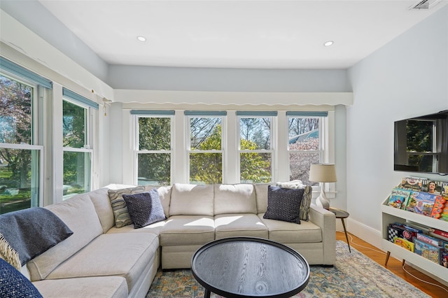 living area with baseboards, wood finished floors, and recessed lighting
