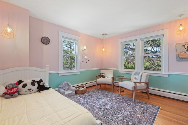 bedroom featuring wood finished floors and a baseboard heating unit