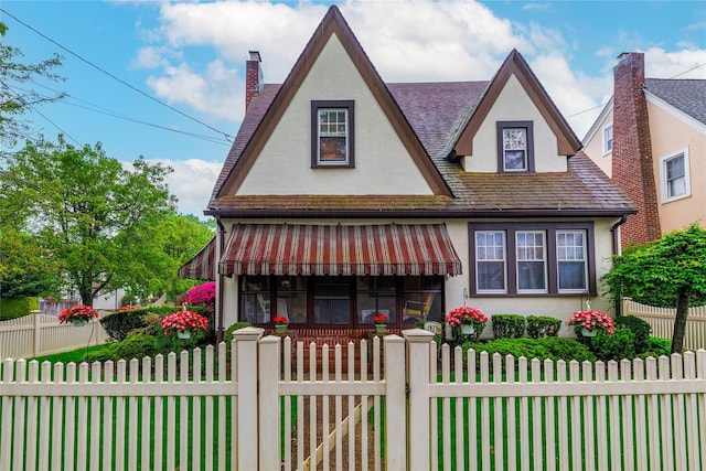1875 Harte St, Baldwin, NY 11510 - tudor home featuring stucco siding, a chimney, a fenced front yard, and a gate