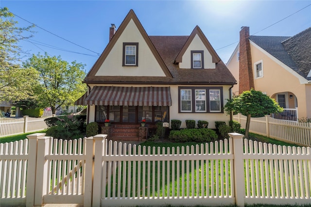 1875 Harte St, Baldwin, NY 11510 - english style home featuring stucco siding, a chimney, a fenced front yard, and roof with shingles
