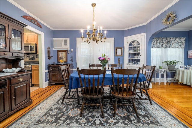 1875 Harte St, Baldwin, NY 11510 - dining room featuring a chandelier, light wood-style floors, a wall mounted air conditioner, ornamental molding, and arched walkways