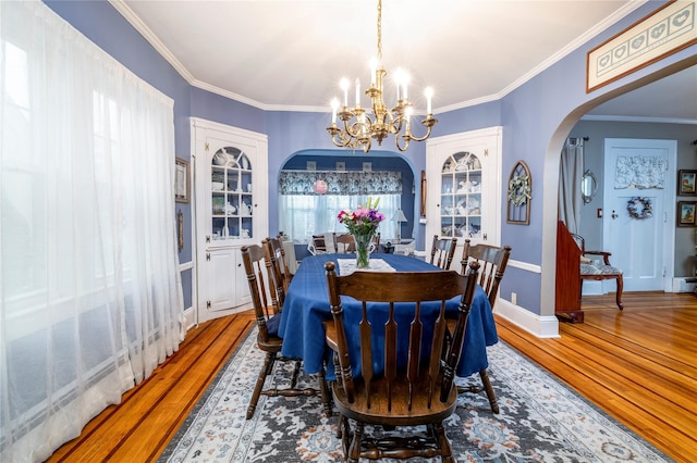 1875 Harte St, Baldwin, NY 11510 - dining space with wood finished floors, a chandelier, arched walkways, ornamental molding, and baseboards