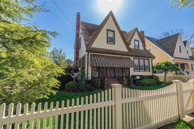 1875 Harte St, Baldwin, NY 11510 - tudor house featuring stucco siding, a fenced front yard, a chimney, and a shingled roof